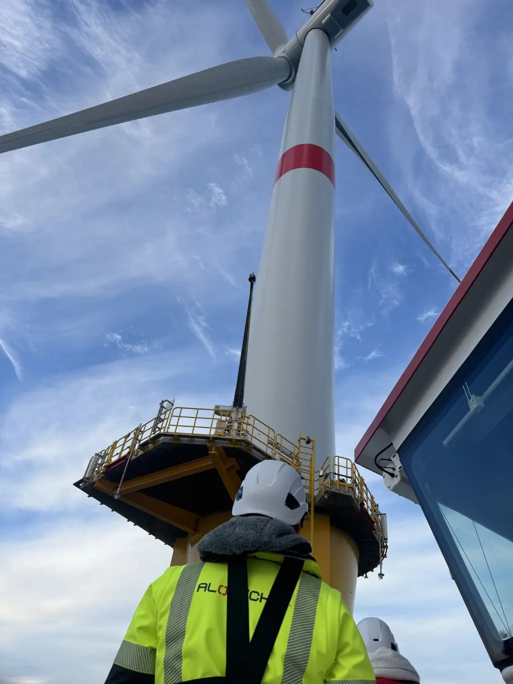 ALOTECH devant une éolienne offshore Hun homme devant une éolienne offshore